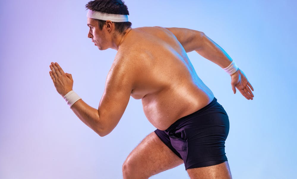 Ein leicht übergewichtiger Mann rennt, während sein Bauch sichtbar ist, und versucht, durch Sport abzunehmen