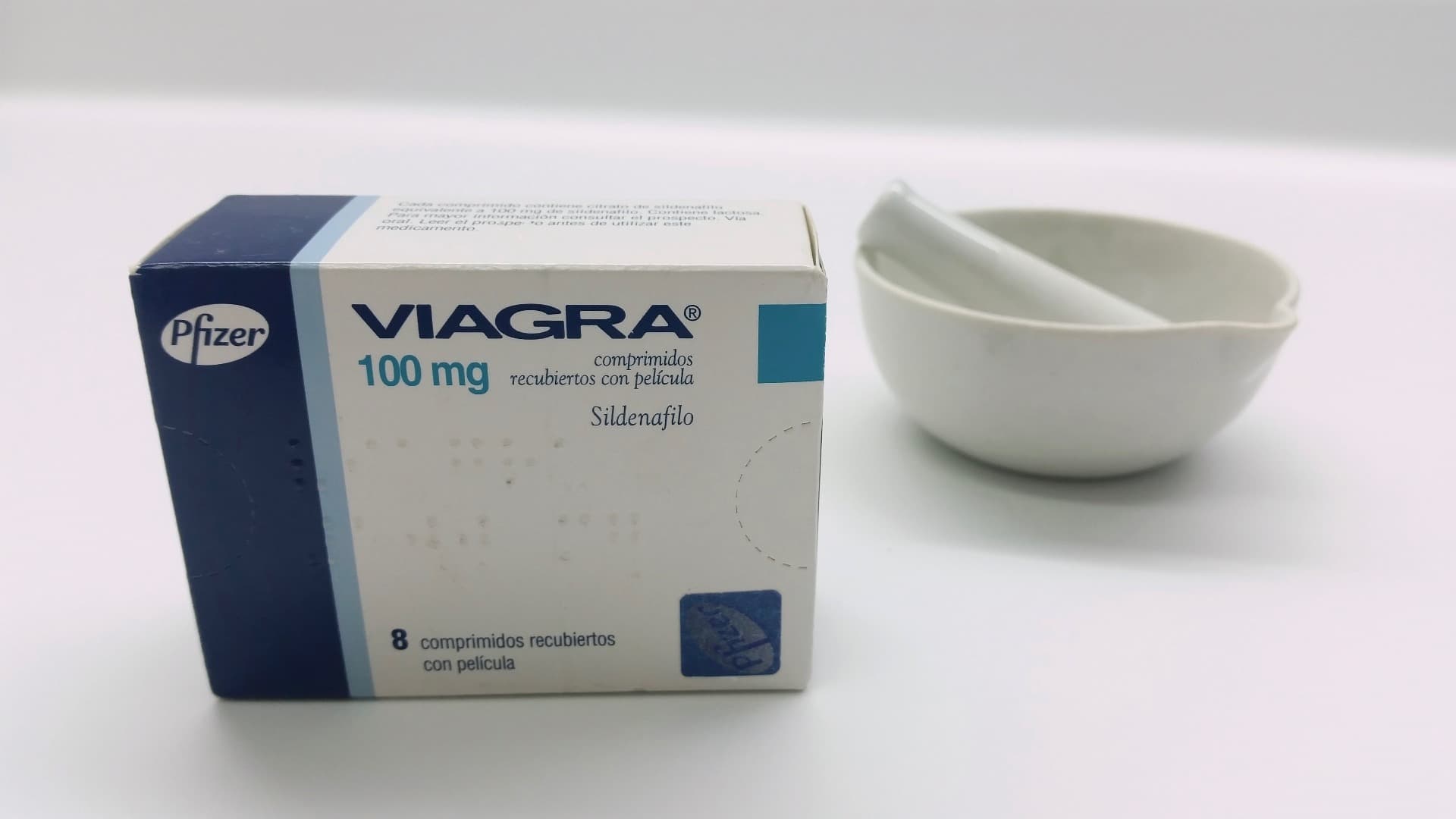 Die Verpackung einer Viagra-Pille (die blaue Pille) auf einem Tisch neben Stößel und Mörser