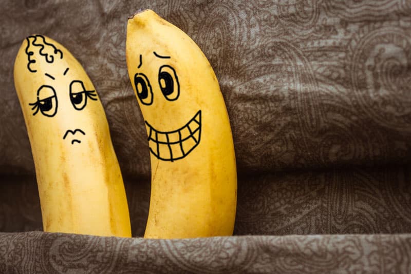 Zwei Bananen mit ausdrucksvollen Gesichtern. Eine lächelt. Eine ist verärgert.