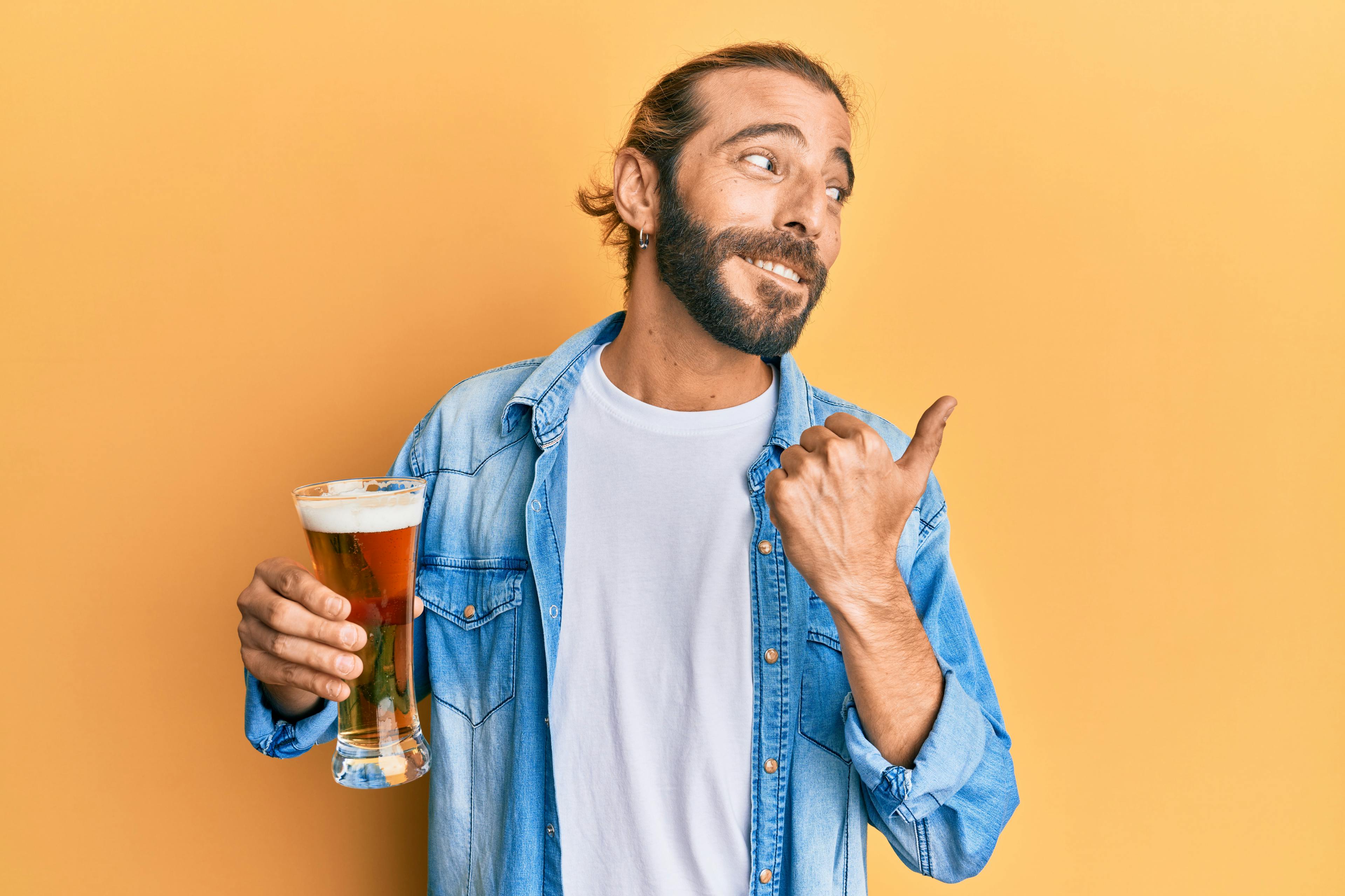 Ein Mann hält ein Bier in der Hand. Er hat ein freches Lächeln auf seinem Gesicht