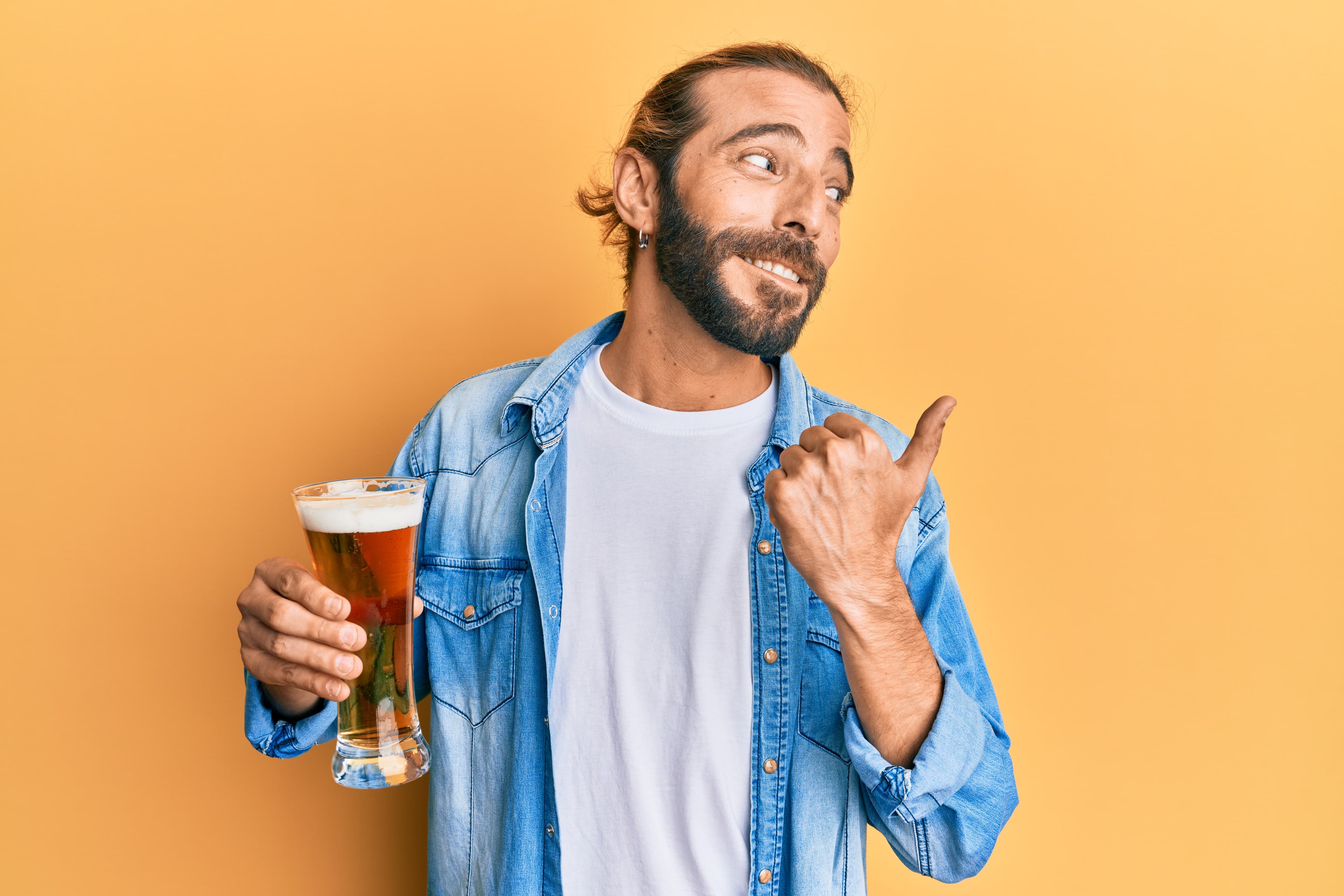 Ein Mann hält ein Bier in der Hand. Er hat ein freches Lächeln auf seinem Gesicht