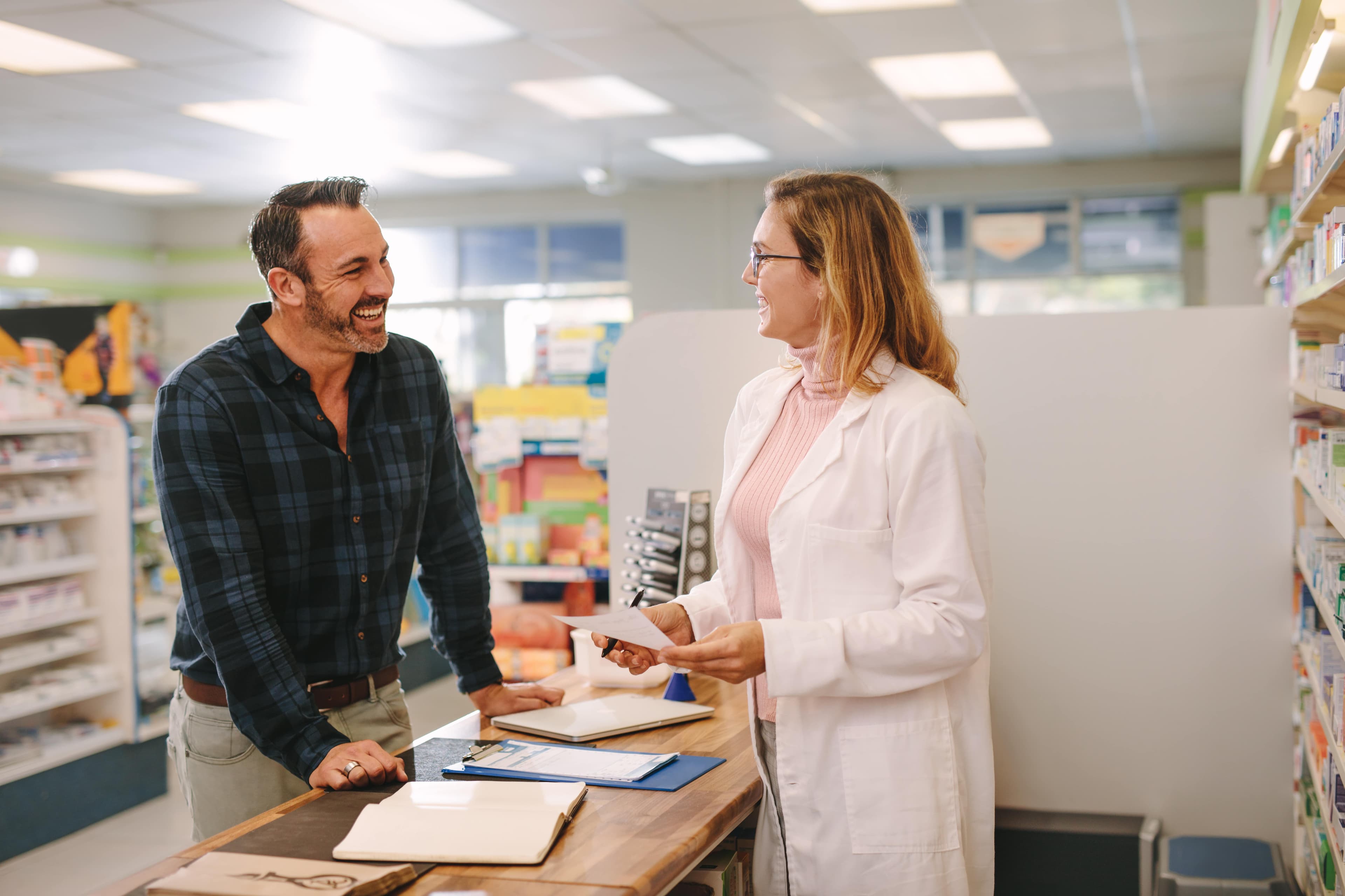 Ein Apotheker im Gespräch mit einem Patienten in einer Apotheke.