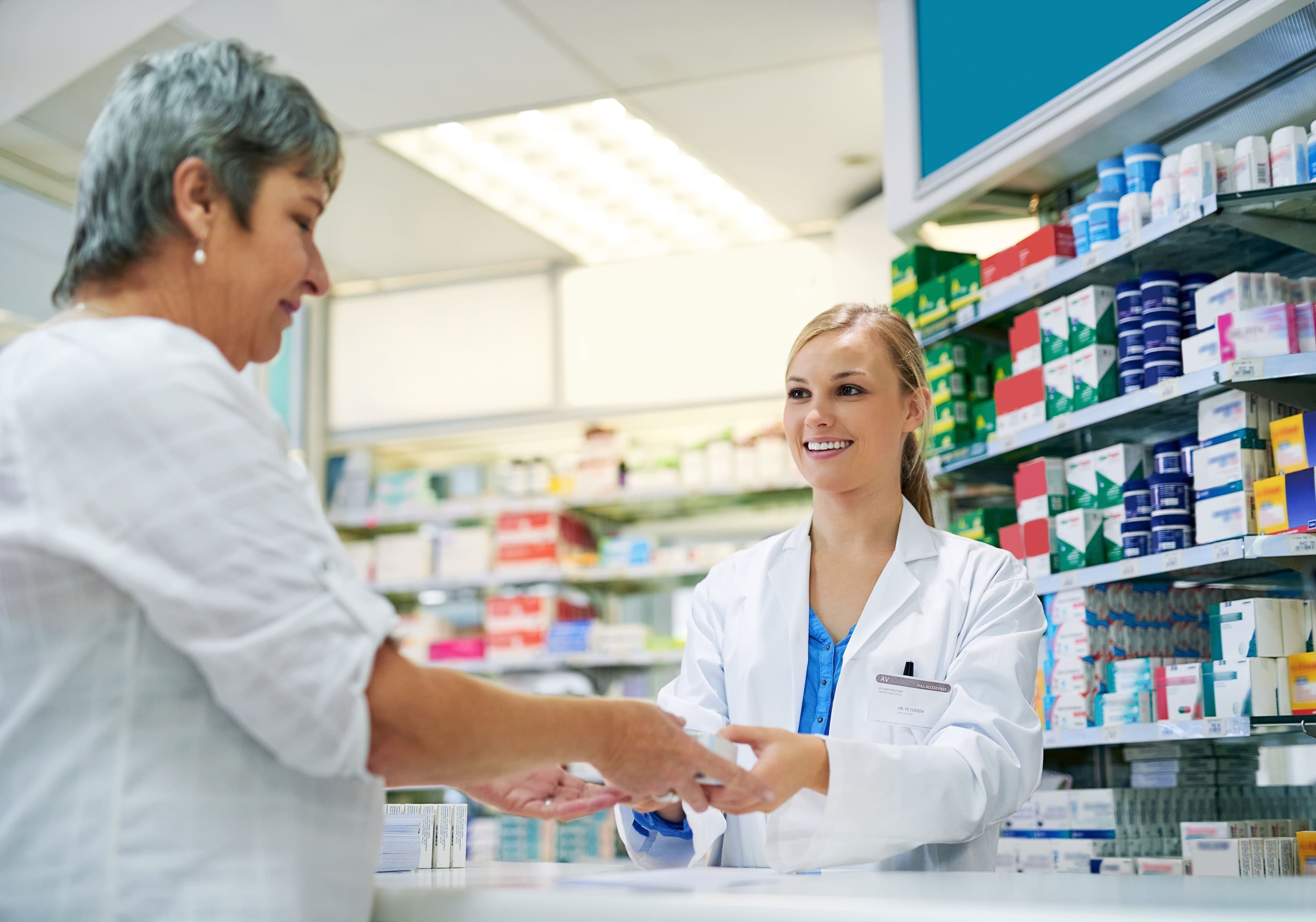 Ein Apotheker gibt einem Patienten seine Medikamente.