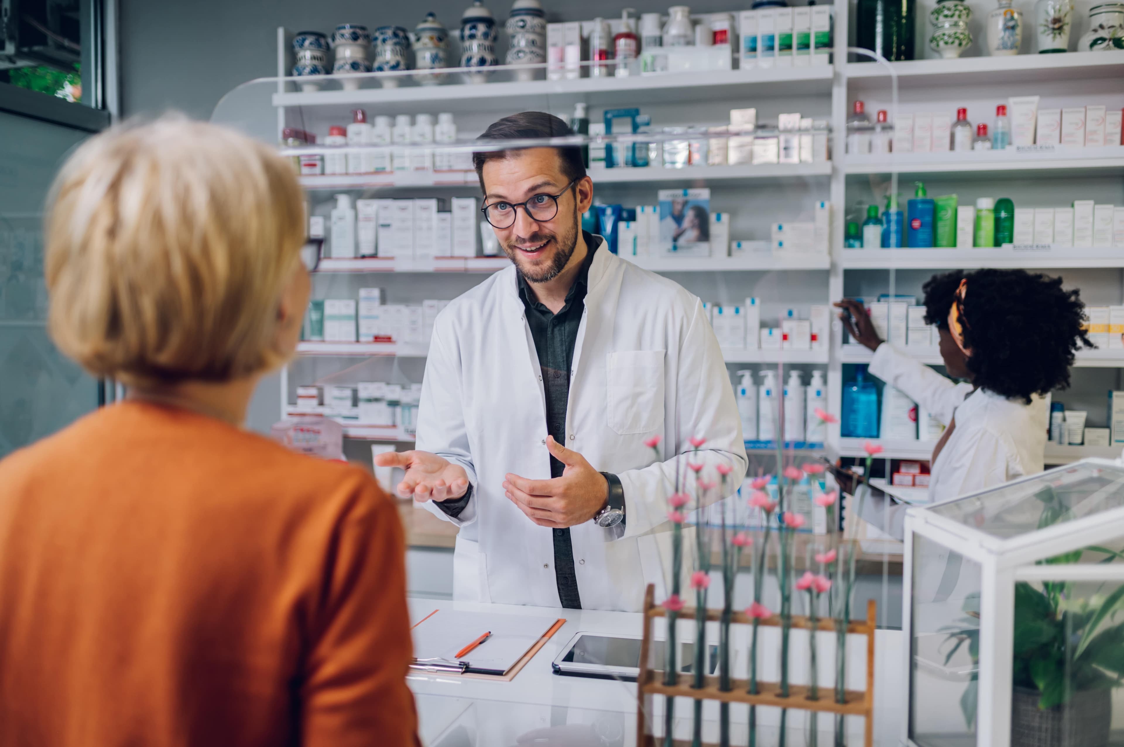 Ein Apotheker, der einem Patienten in einer Apotheke ein Medikament empfiehlt.