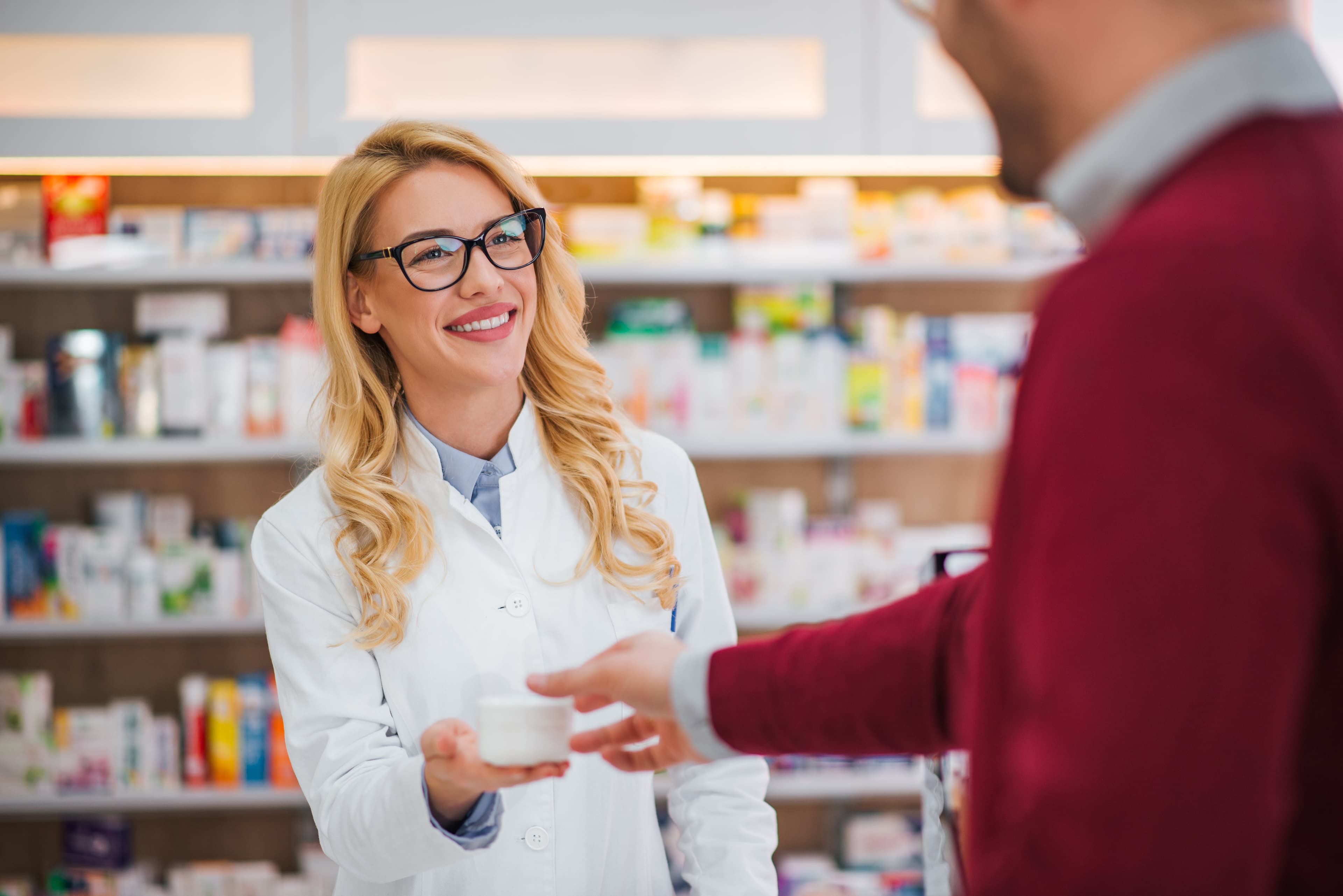 Ein Apotheker, der einem Patienten in einer Apotheke Medikamente anbietet.