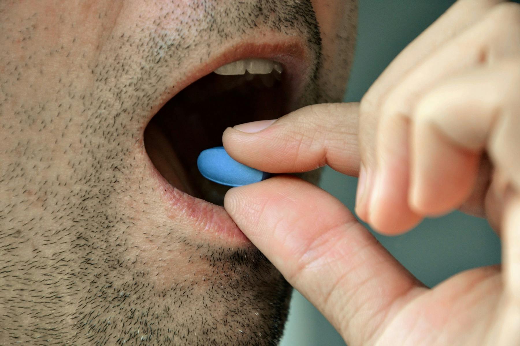 Ein Mann, der eine blaue Viagra-Pille schluckt