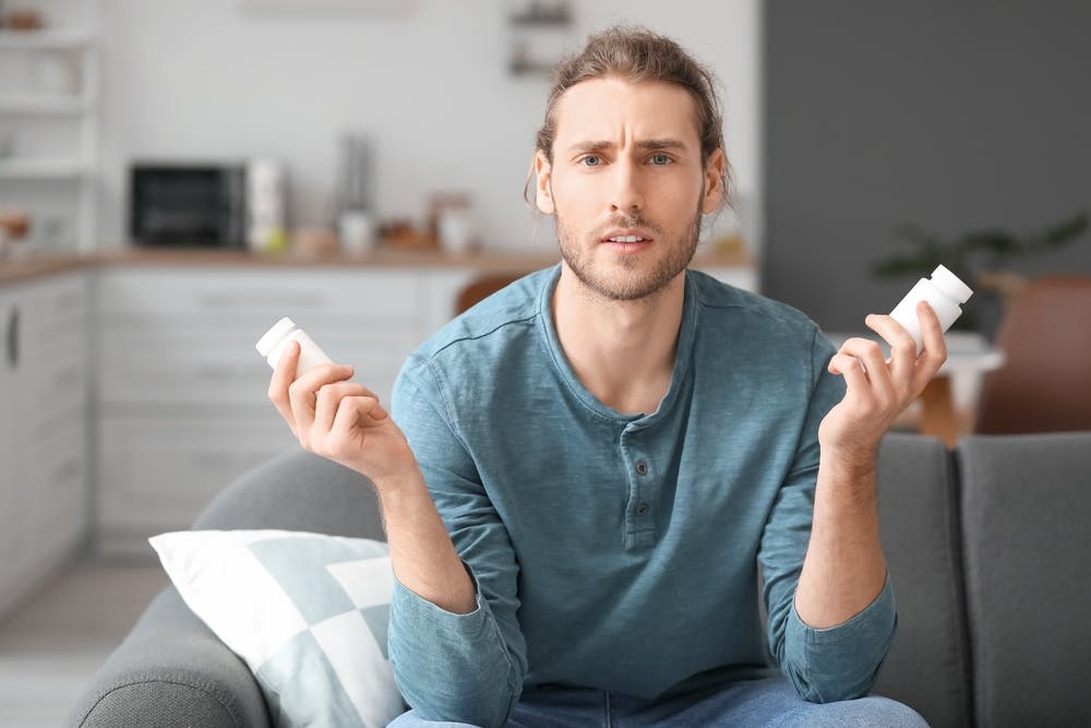 Ein Mann hält zwei Pillenflaschen mit Viagra (Sildenafil)